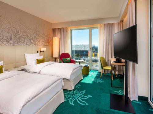 斯图加特Mövenpick Hotel Stuttgart Messe & Congress的酒店客房设有两张床和一台平面电视。