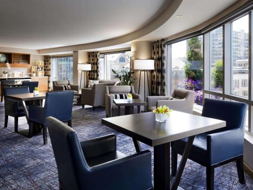 温哥华Fairmont Waterfront的酒店大堂设有桌椅和窗户。