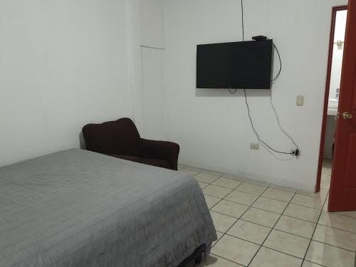 危地马拉Hotel Bluehouse的卧室配有一张床,墙上配有电视。