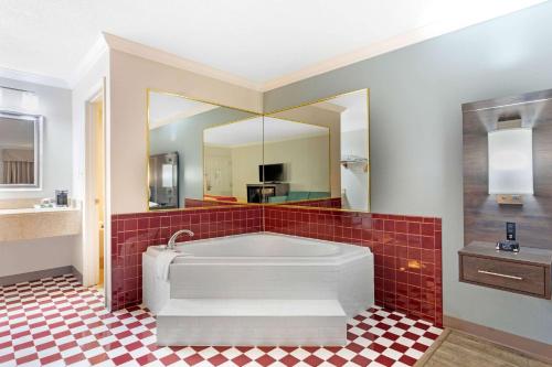 拜伦Econo Lodge Byron - Warner Robins的带浴缸的大浴室和红色瓷砖地板。