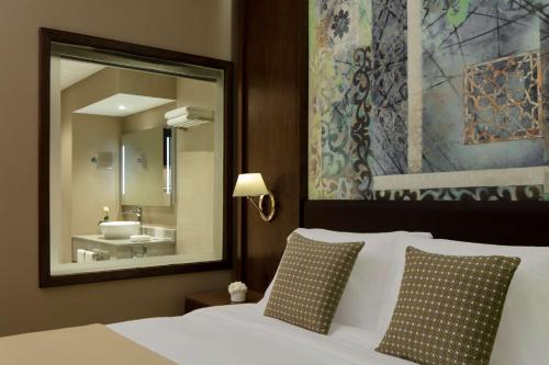 索哈尔Radisson Blu Hotel & Resort, Sohar的一间卧室配有一张带镜子和水槽的床