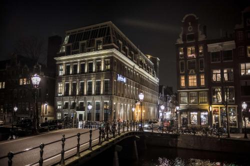 阿姆斯特丹Radisson Blu Hotel, Amsterdam City Center的夜行的街道,有建筑物和桥梁