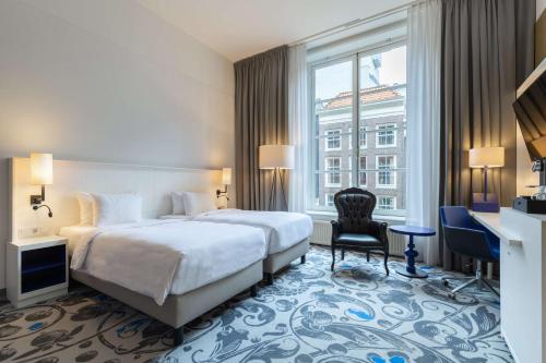 阿姆斯特丹Radisson Blu Hotel, Amsterdam City Center的配有一张床、一张书桌和一扇窗户的酒店客房