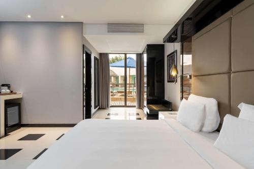 卢萨卡卢萨卡丽笙酒店的一间带一张白色大床的卧室和一个阳台
