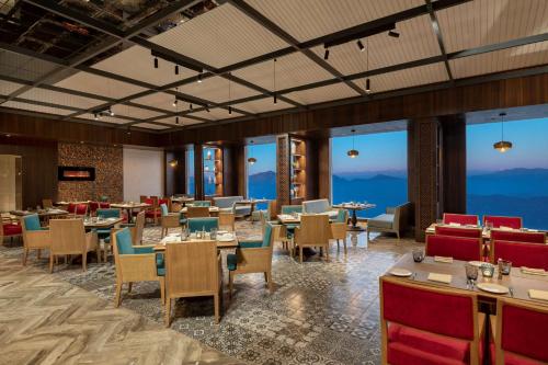 西姆拉Radisson Kufri的餐厅配有桌椅,位于山脉的背景中
