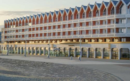 敦刻尔克Radisson Blu Grand Hotel & Spa, Malo-Les-Bains的一座白色的大建筑,有很多窗户