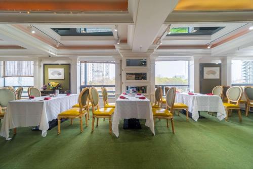 宜昌华美达宜昌大酒店的一间设有白色桌子和黄色椅子及窗户的客房