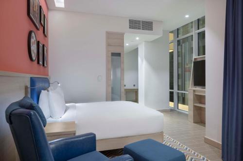多哈Hampton By Hilton Doha Old Town的卧室配有白色的床和蓝色椅子