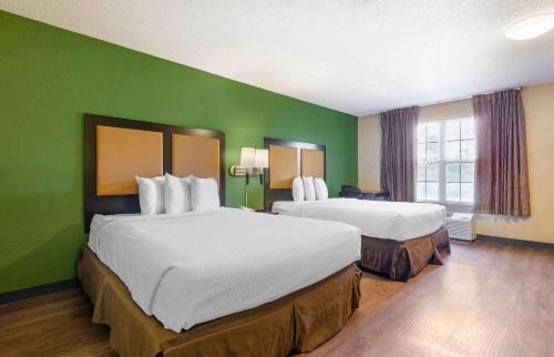 罗阿诺Extended Stay America Select Suites - Roanoke - Airport的酒店客房设有两张床和绿色的墙壁。