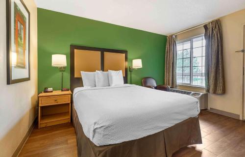 森特尼尔美国长住酒店 - 丹佛 - 科技中心南 - 因弗内斯的酒店客房设有一张大床和绿色的墙壁。