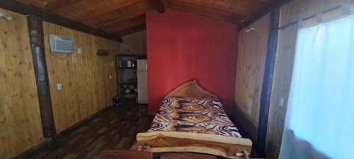 Puerto BossettiCabañas Libertad en Misiones的红色墙壁的房间里一张床位