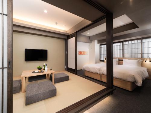 京都MIMARU KYOTO NISHINOTOIN TAKATSUJI的一间卧室配有一张床、一张桌子和一台电视。