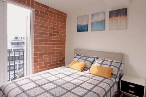 危地马拉Encantador y Panorámico Apartamento的一间卧室配有带两个枕头的床和砖墙