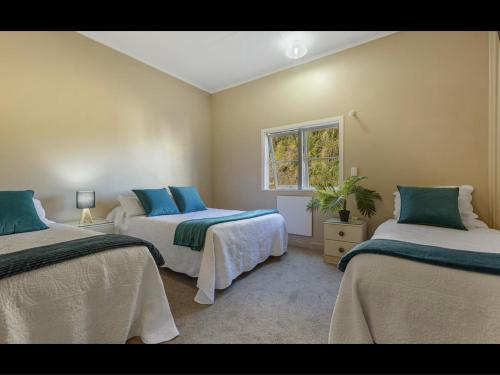 WhangaroaFISHERMANS’DELIGHT的一间卧室设有两张床和窗户。