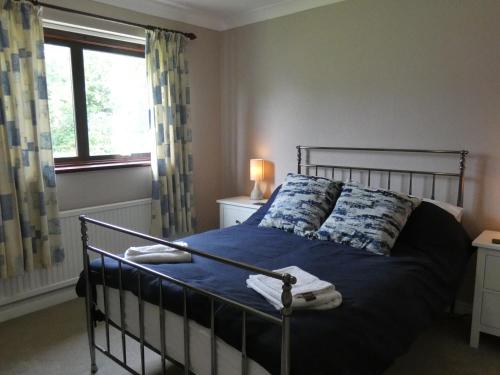 约克Red Tree Cottage的一间卧室配有一张带蓝色床单的床和一扇窗户。