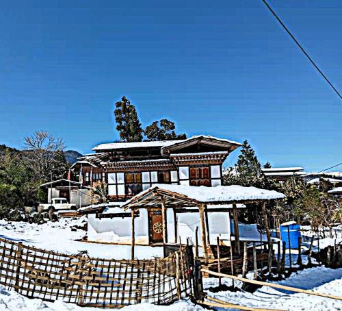 普纳卡Nobgang B&B "Traditional Heritage HomeStay"的前面的地面上积雪的房子