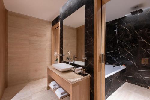 多哈The Bentley Luxury Hotel & Suites的一间带水槽和浴缸的浴室