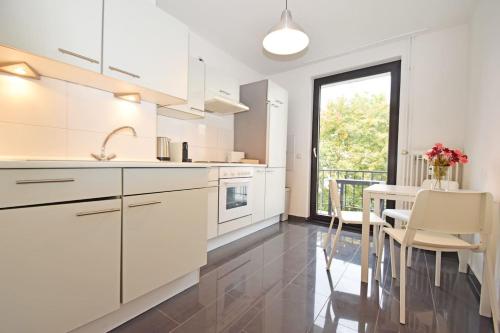 不莱梅Air Apartments 1的厨房配有白色橱柜和桌椅