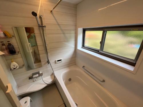 大岛田园之家度假屋的带浴缸和窗户的浴室