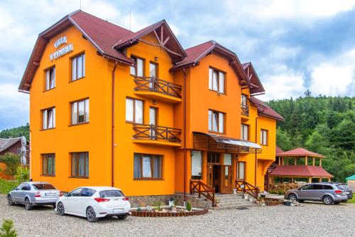 亚西尼亚У Румуна的一座橙色的建筑,前面有汽车停放