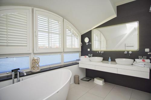 特伦特Haus in idyllischer Lage mit Sauna, Terrasse und Garten - Villa Morgensünn的浴室配有2个盥洗盆、浴缸和镜子
