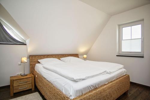特伦特Haus in idyllischer Lage mit Sauna, Terrasse und Garten - Villa Morgensünn的一间卧室配有一张带白色床单的床和一扇窗户。