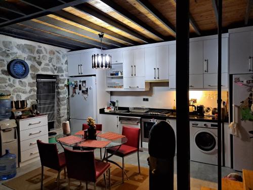 凯麦尔Çiftlik ve Dağ evi Kemer - Canerbey的厨房配有白色橱柜和桌椅