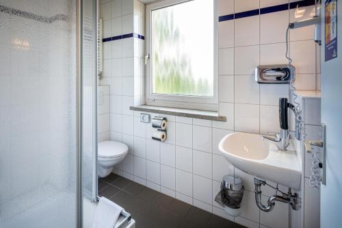 魏玛魏玛A&O酒店的一间带水槽和卫生间的浴室以及窗户。
