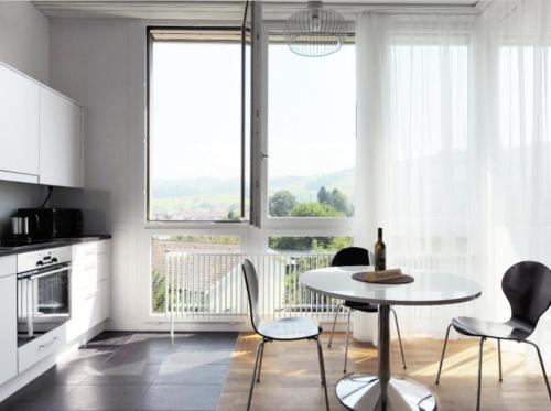 楚格Nest - Baarerstrasse 82的厨房配有桌椅和窗户。