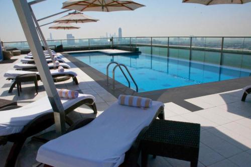 迪拜瑞吉斯公园克里斯金酒店的一座大楼内的游泳池,配有椅子和遮阳伞