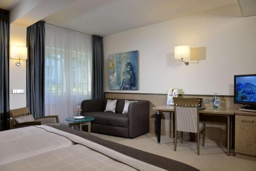 汉诺威康斯柏格西佳高级公园酒店的酒店客房配有床、沙发和电视。