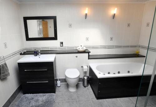 阿斯克Luxury property - Swimming Pool, Games Room & Hot Tub的带浴缸、卫生间和盥洗盆的浴室