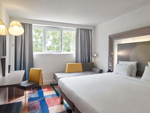 塞尔吉B&B HOTEL Cergy Port 4 étoiles的酒店客房设有一张大床和一张书桌。