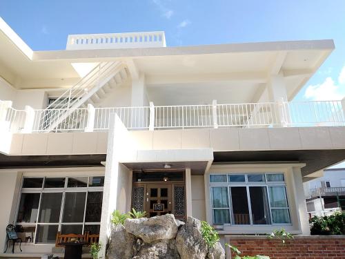 宫古岛フェーヌカジ洋室的白色的房子,上面设有阳台