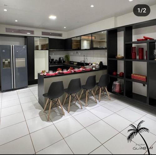 盖比姆Casa LUXO Guaibim的厨房配有黑色橱柜和带椅子的柜台。