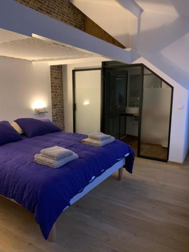 里尔galerie jacqueline storme的一间卧室配有一张紫色床和毛巾