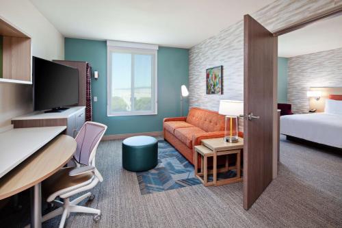 阿拉米达Home2 Suites By Hilton Alameda Oakland Airport的酒店客房配有一张床、一张沙发和一张书桌。