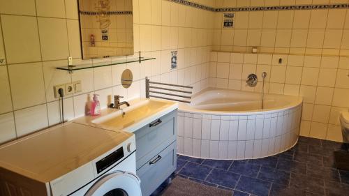 卑尔根Ferienwohnung Bergfreunde的带浴缸、水槽和洗衣机的浴室