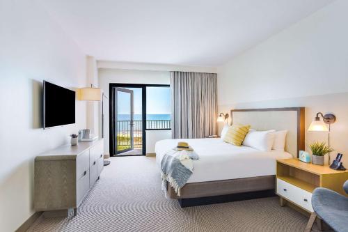 格尔夫海岸The Lodge at Gulf State Park, A Hilton Hotel的酒店客房设有一张大床和一个阳台。