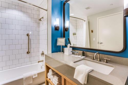 格尔夫海岸The Lodge at Gulf State Park, A Hilton Hotel的一间带水槽、浴缸和镜子的浴室