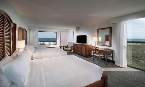 奥兰治比奇The Island House Hotel a Doubletree by Hilton的酒店客房设有两张床、一张桌子和一台电视。