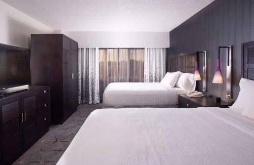 罗利Embassy Suites by Hilton Raleigh Crabtree的酒店客房设有两张床和电视。