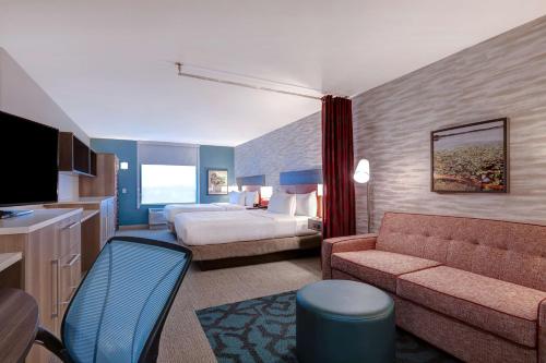 迪卡尔布Home2 Suites By Hilton DeKalb的酒店客房,配有床和沙发