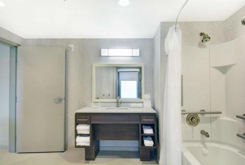 达拉姆Home2 Suites By Hilton Raleigh Durham Airport RTP的浴室配有盥洗盆、镜子和浴缸
