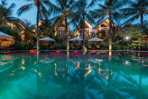 宁平Coco Island Villa & Hotel Ninh Bình的棕榈树游泳池以及酒店