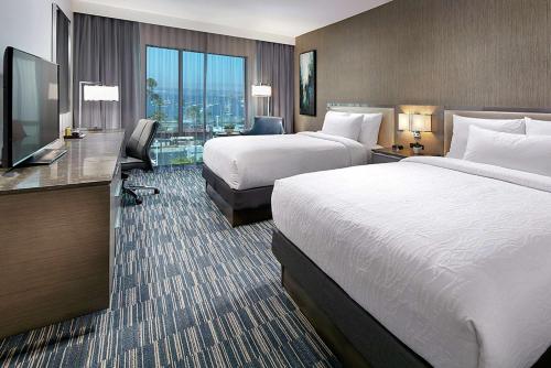 圣地亚哥Hilton Garden Inn San Diego Downtown/Bayside, CA的酒店客房设有两张床和一台平面电视。