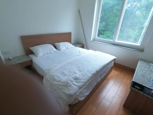 德拉敦OLIVIA HOME STAY的一间卧室配有一张带白色床单的床和一扇窗户。