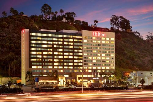 圣地亚哥圣地亚哥米申山谷希尔顿酒店的一座灯光明亮的酒店建筑,后面有一座小山