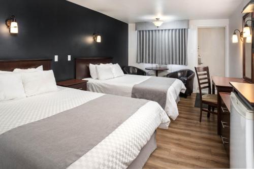 拉图克Hôtel Marineau Centre的酒店客房带两张床和一张桌子以及椅子。