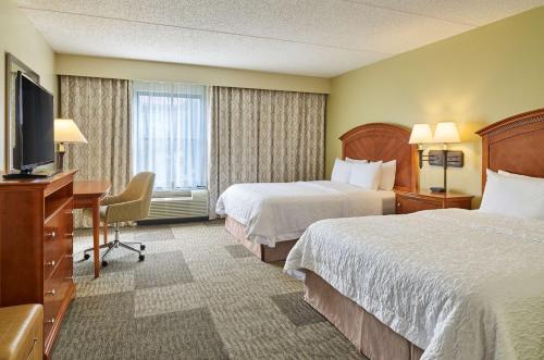 圣安东尼奥Hampton Inn San Antonio Stone Oak的酒店客房设有两张床、一张桌子和一台电视。